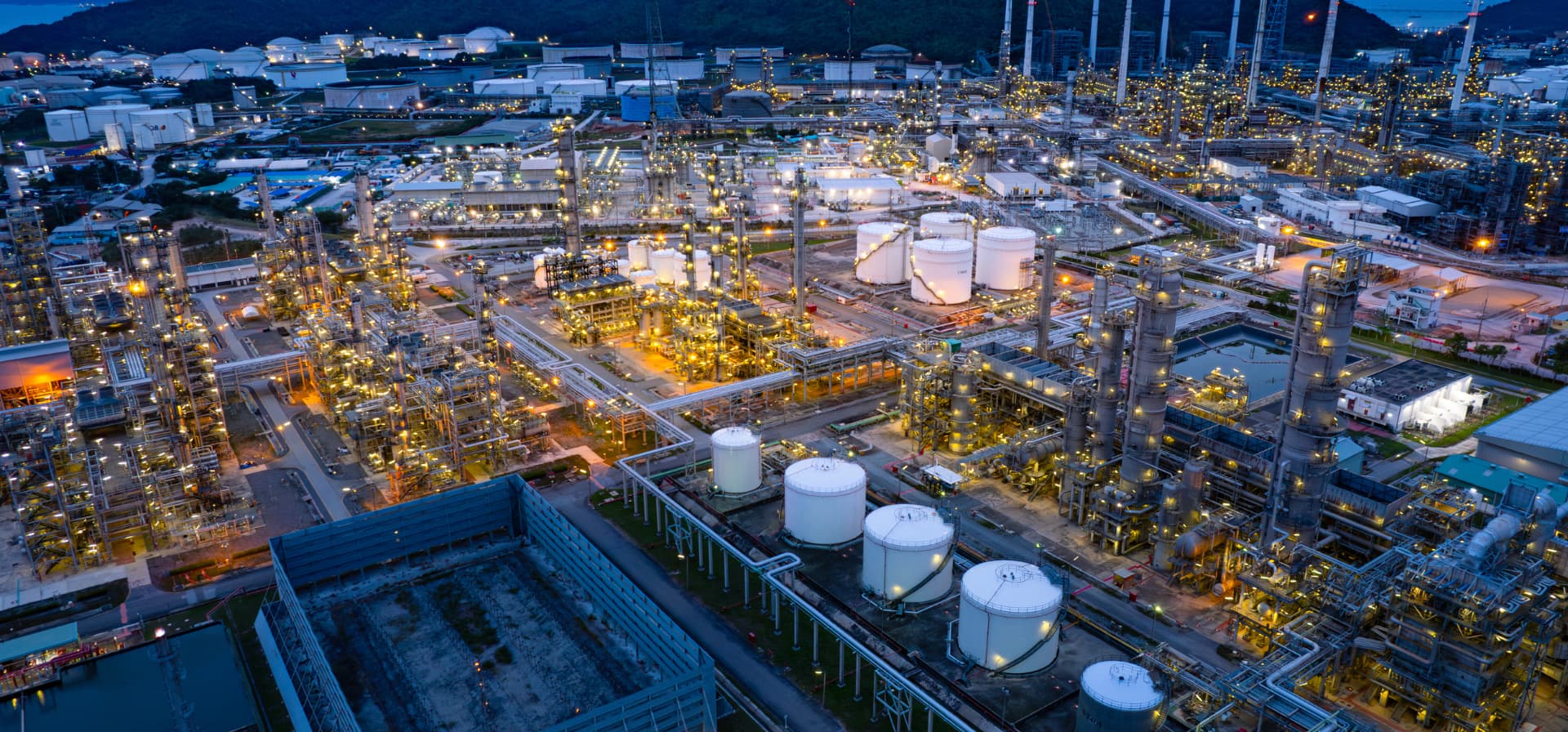 Aerial view of an illuminated oil refinery and petrochemical complex at dusk